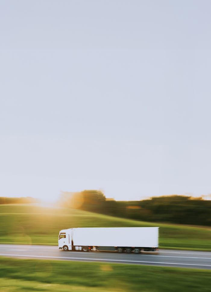 Services White cargo truck speeding through Vitebsk countryside at sunrise, symbolizing transportation and logistics.