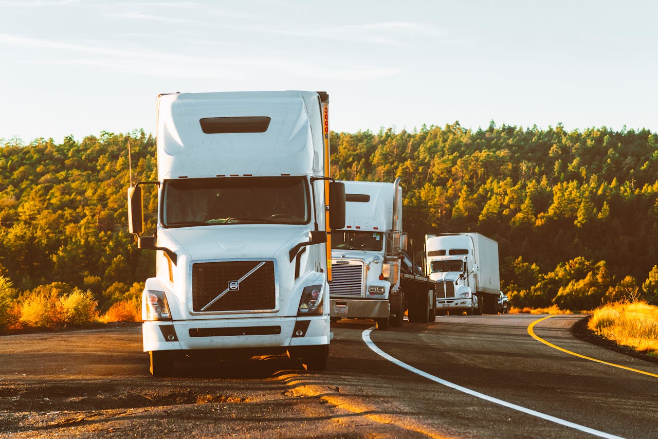 Home Three semi trucks driving on a highway through a forested landscape in Arizona.